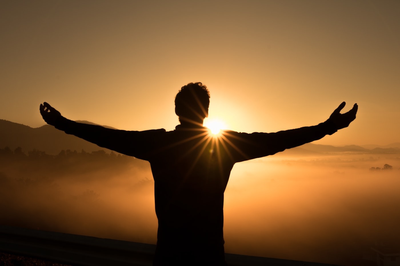 A figure with open arms greeting the sunrise