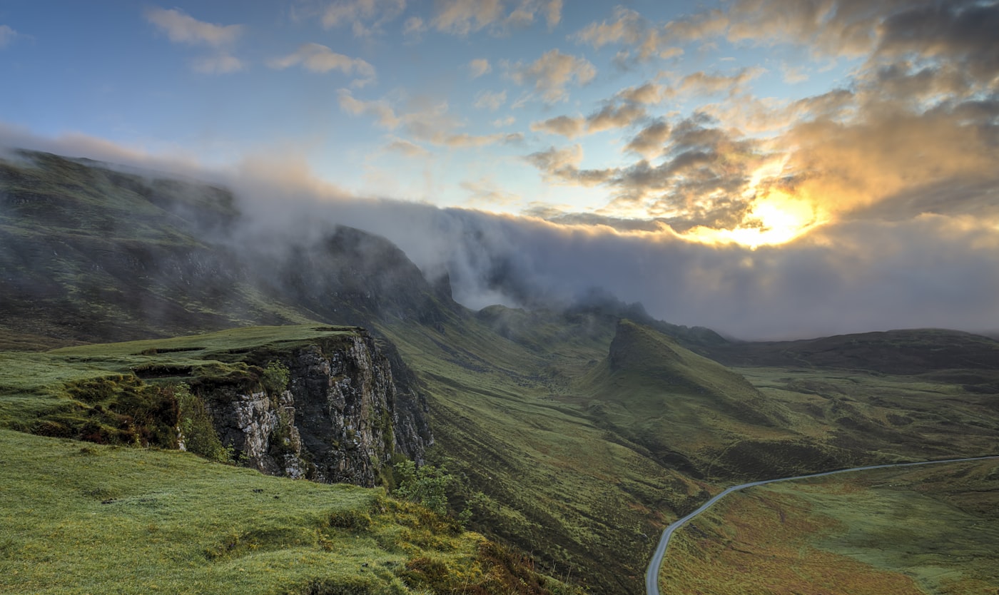 Green valleys and ridgelines under a soft sunrise