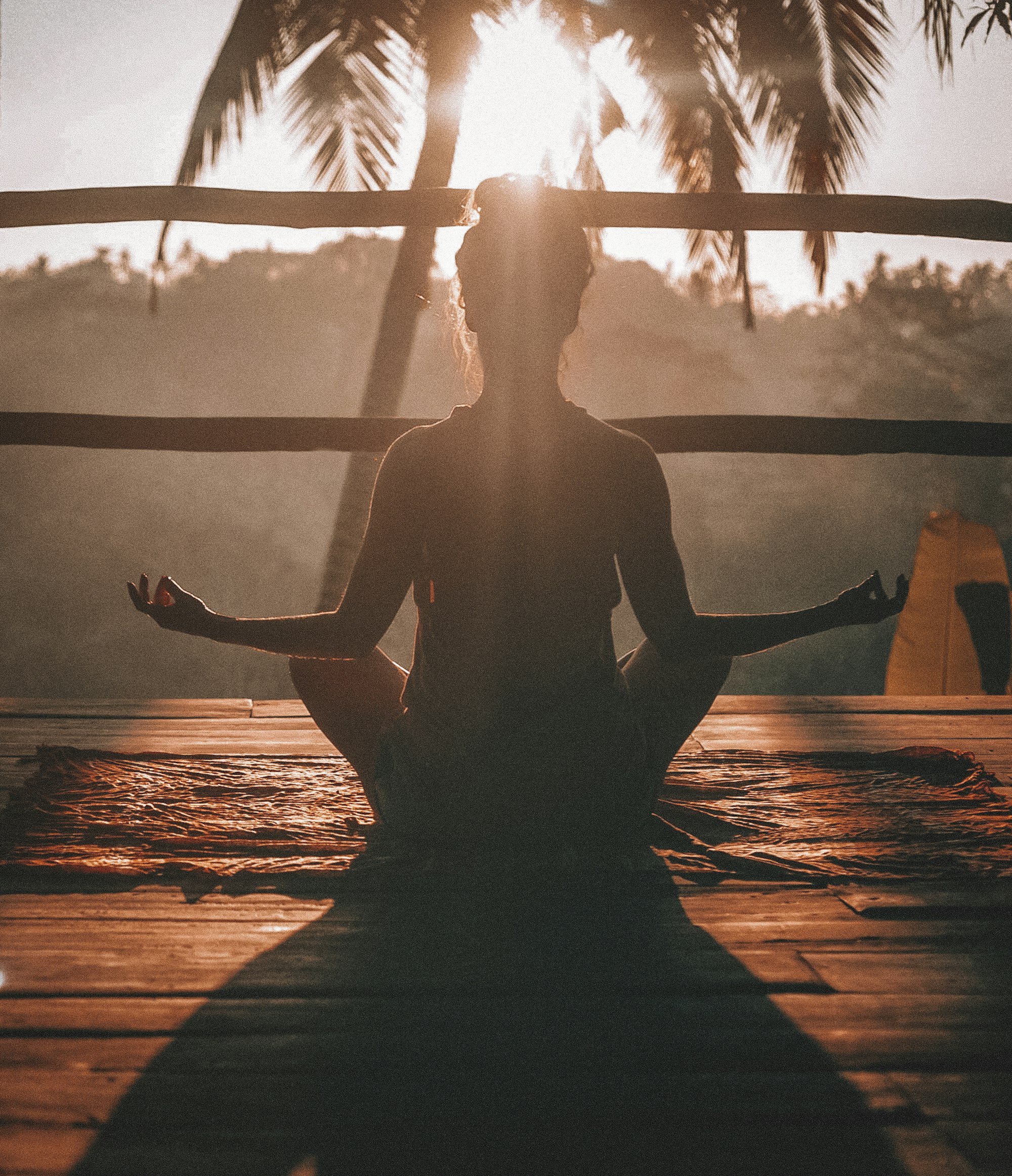 A silhouetted figure meditating cross-legged at sunrise