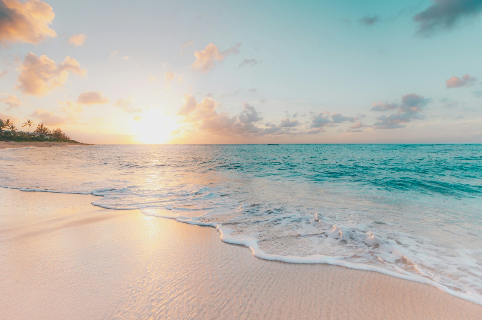 A soft sunrise over gentle waves on an empty beach